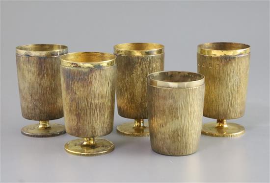 Adrian Gerald Benney. A set of four bark effect silver gilt goblets, on short stems and a similar tumbler, 36.5 oz.